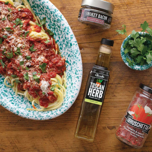 Spaghetti dish with various seasoning jars on a wooden table