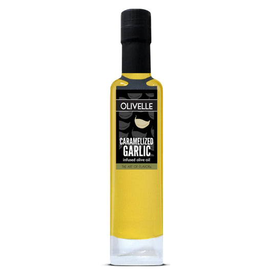 A bottle of Olivelle Caramelized Garlic infused olive oil, featuring a clear glass bottle filled with golden yellow oil, a black cap, and a black label with white text.